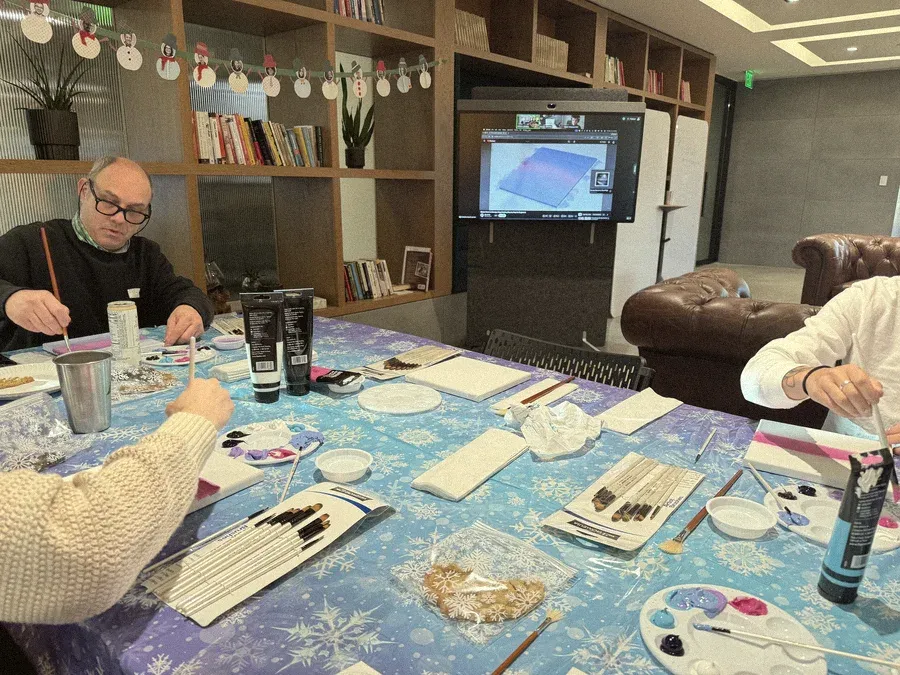 Teammates painting at a table covered in a snowflake cloth